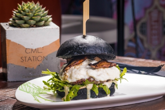 桌上盘子里黑色面包夹着的大汉堡美食摄影