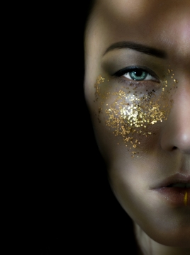 黑色背景时尚女性面部金色闪粉