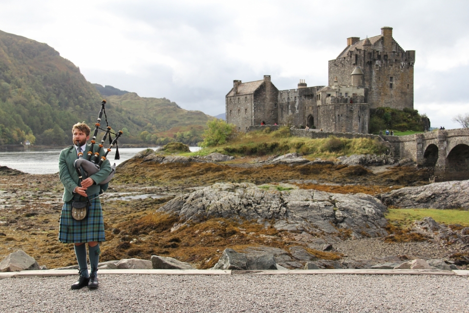 中世纪古堡前吹苏格兰风笛的男子