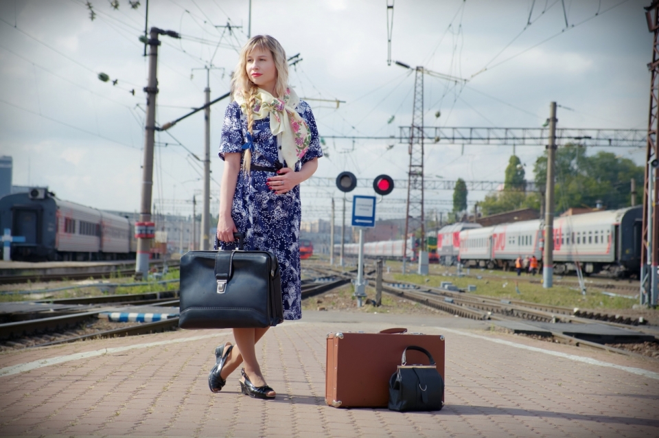 碎花长裙女子站在火车站台提着皮包和箱子