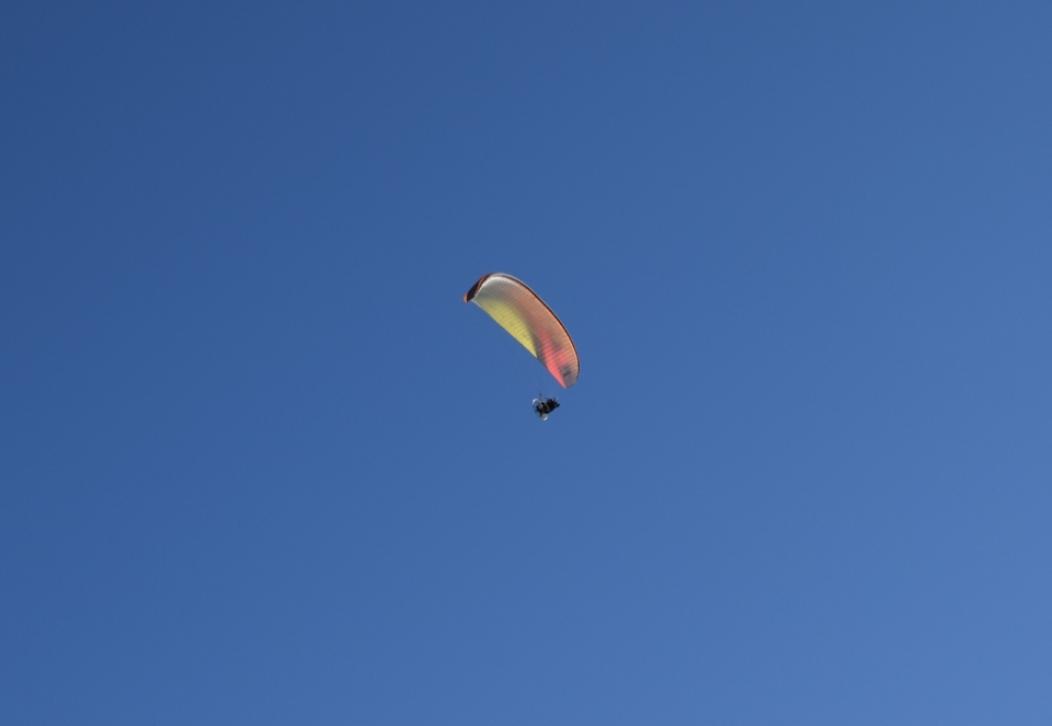 蓝色天空中滑行的滑翔伞运动员