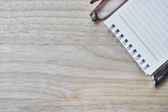 原木色办公桌上空白笔记本和眼镜