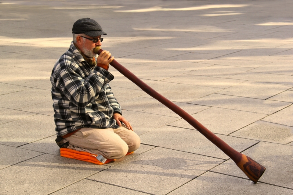 人物摄影_城市街道老年男性坐地面吹奏传统乐器