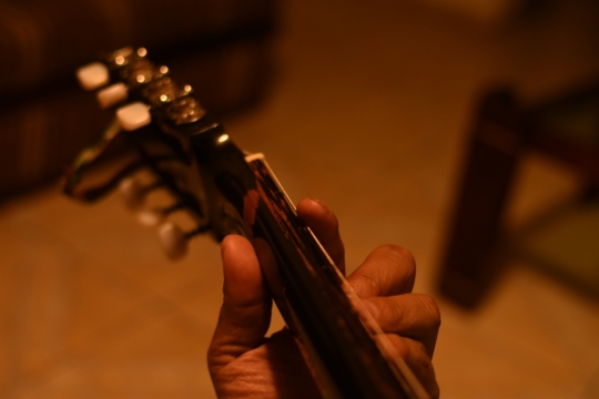 昏暗的灯光下弹奏吉他的手特写