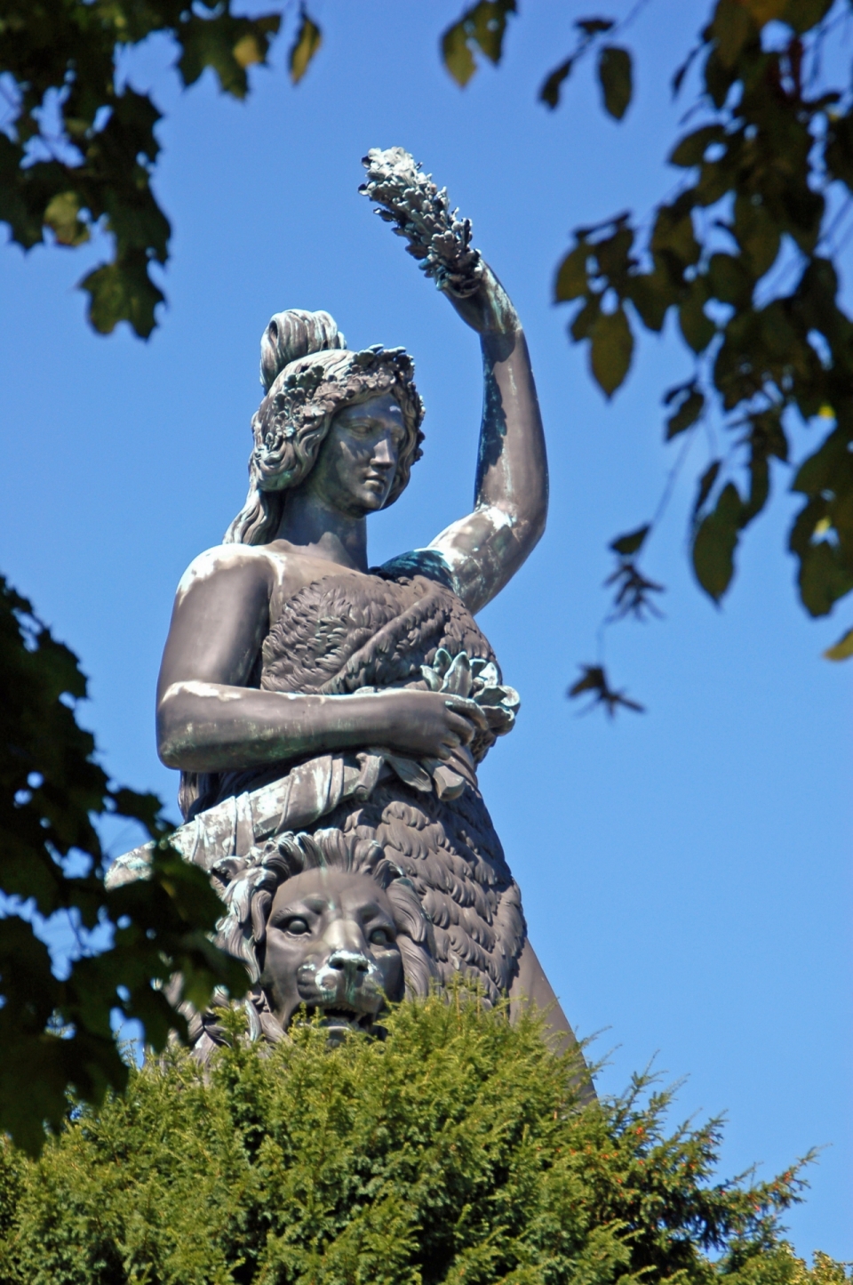 城市蓝天树木间破损女性艺术雕像