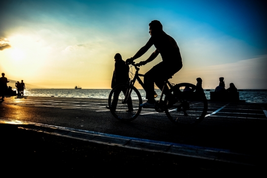 夕阳海岸边公路上骑的人剪影摄影