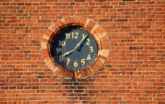 红砖墙面镶嵌黑色时钟指针特写