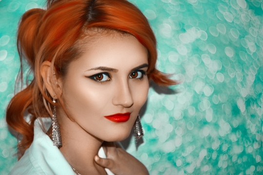 室内绿色背景前戴时尚耳饰长发美女