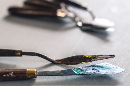 室内灰色桌面沾颜料木制柄金属刮刀