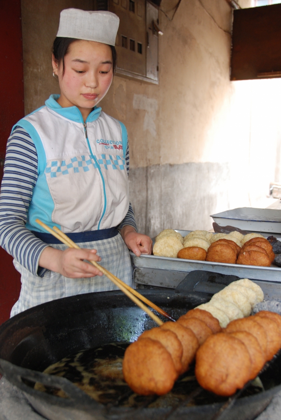 油锅前炸面饼的少数民族少女