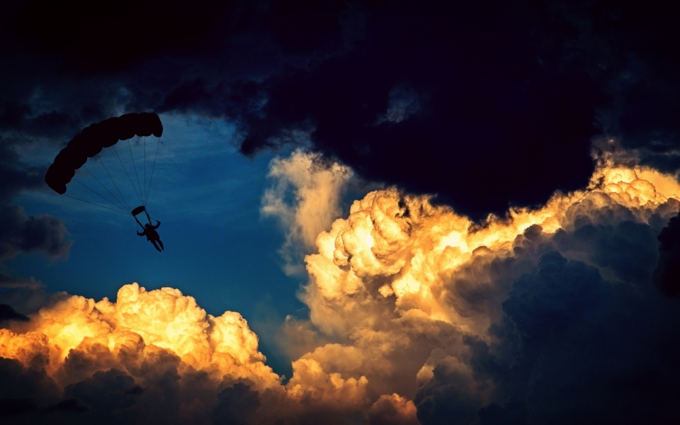 在光明漆黑的云层中打开降落伞的跳伞员