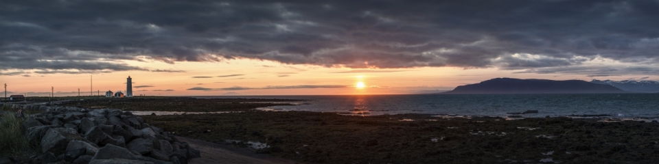 夕阳照射下的海岸浅滩与远处的灯塔