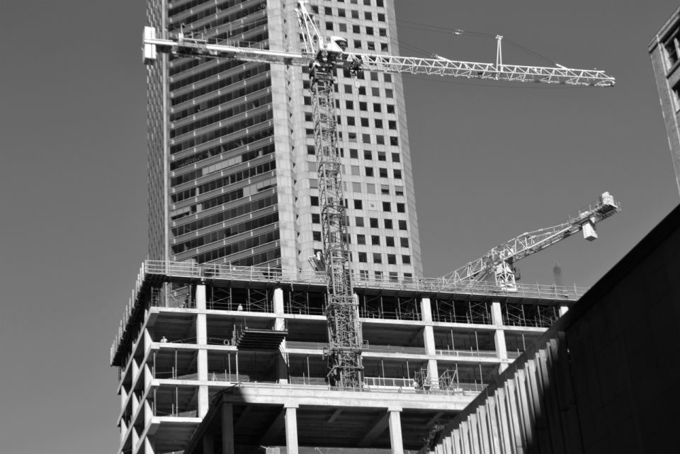 黑白城市高楼大厦旁建筑工事的吊车
