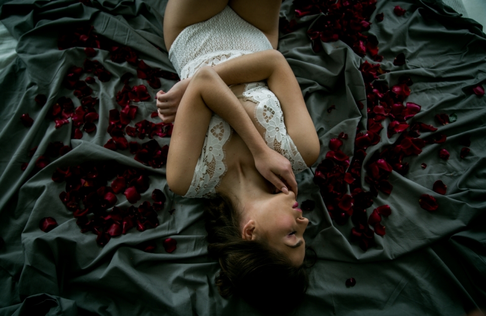 躺在黑色床上睡觉的性感美女洒满玫瑰花瓣