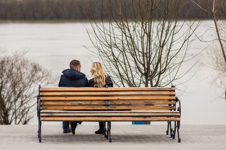 冬季结冰湖边木制长凳情侣背影