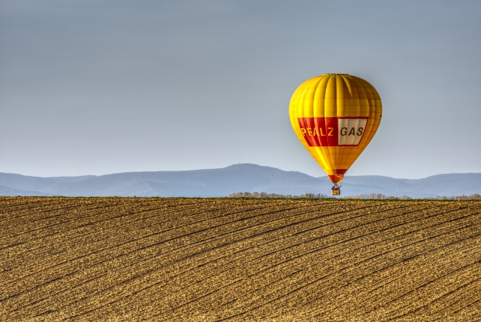 在金黄色的麦田上飞行的热气球摄影