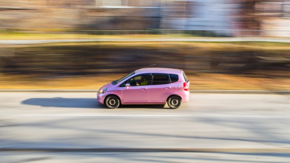 城市街道马路疾驰粉色轿车