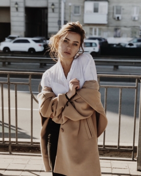 马路边依靠在栏杆上穿着大衣的美女写真