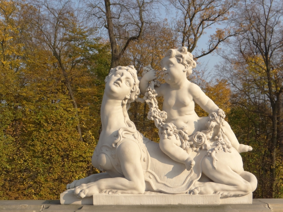 公园中男孩骑女性狮身人面像白色雕像
