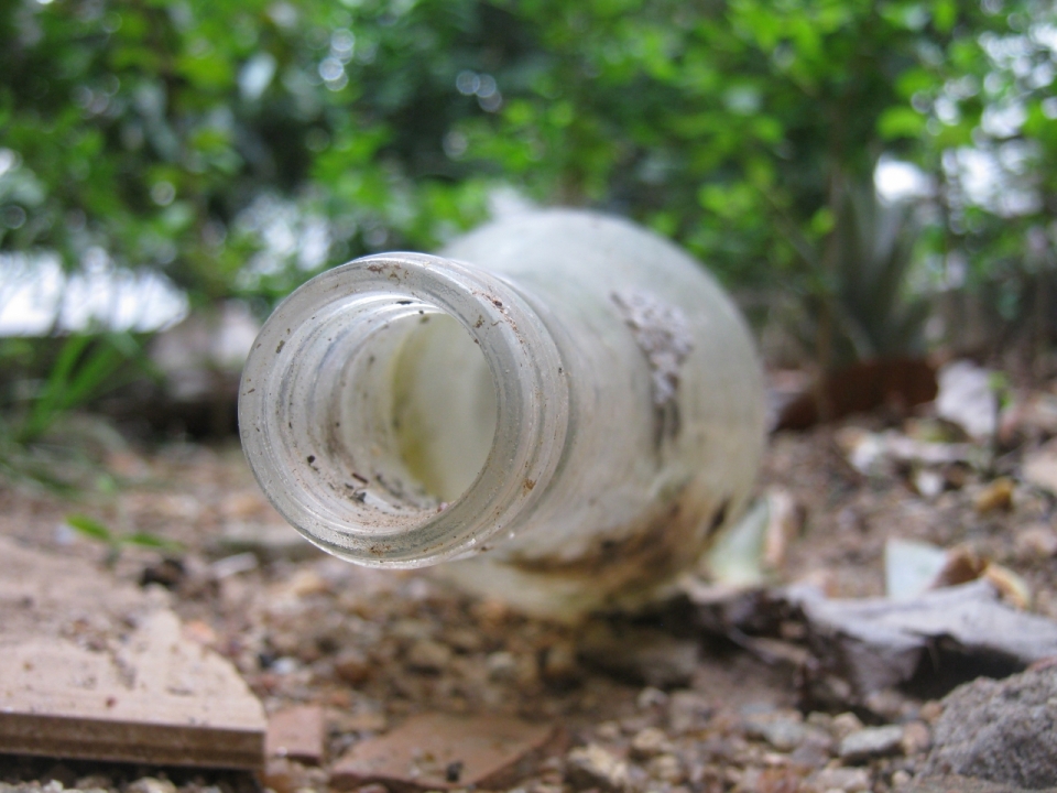 背景虚化倒在泥土上的废弃玻璃瓶静物摄影