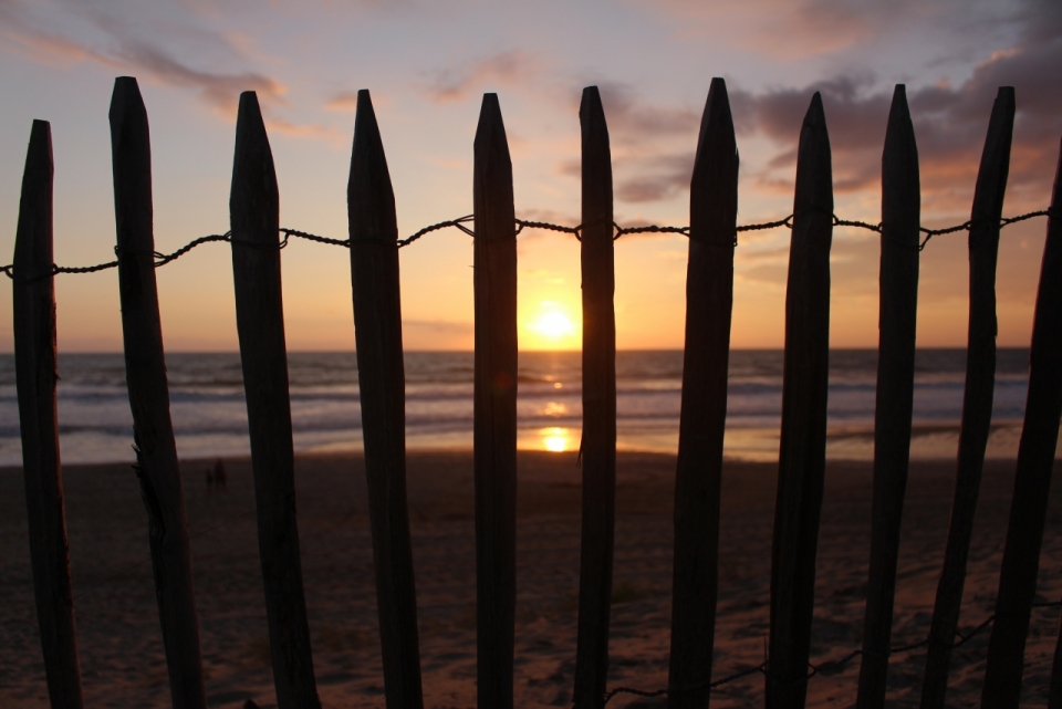 海边沙滩木栏杆后面夕阳西下摄影
