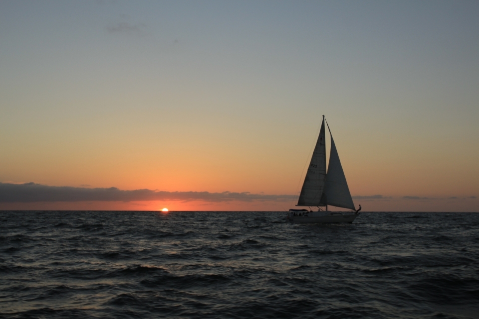 波澜壮阔的大海上一艘孤独的帆船与落日