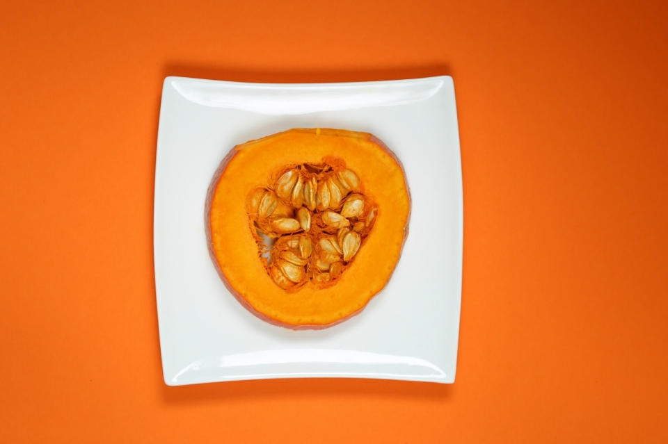 橙色背景白色盘子新鲜南瓜切片