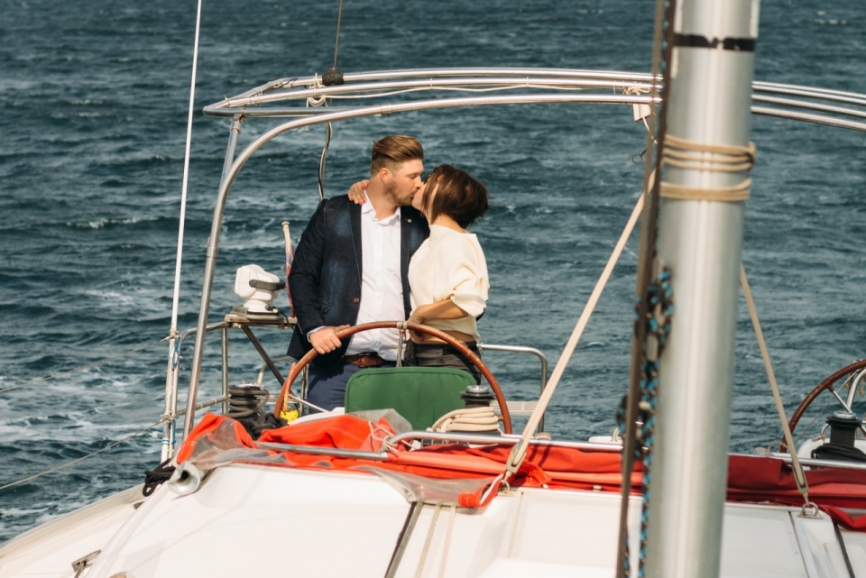 男女情侣边亲吻边驾驶快艇在大海上航行