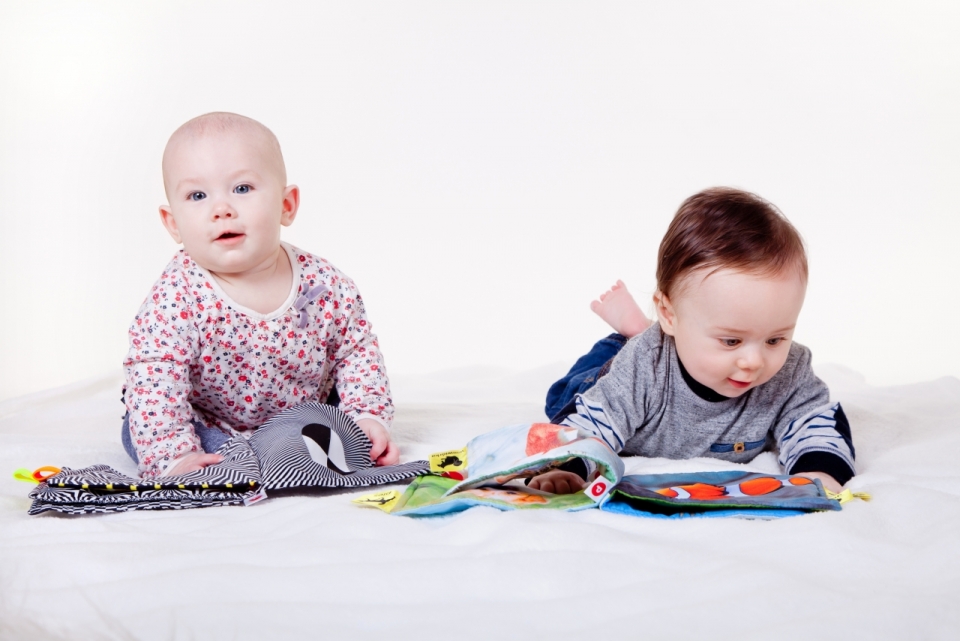 室内白色床铺看彩色布质书本婴儿们