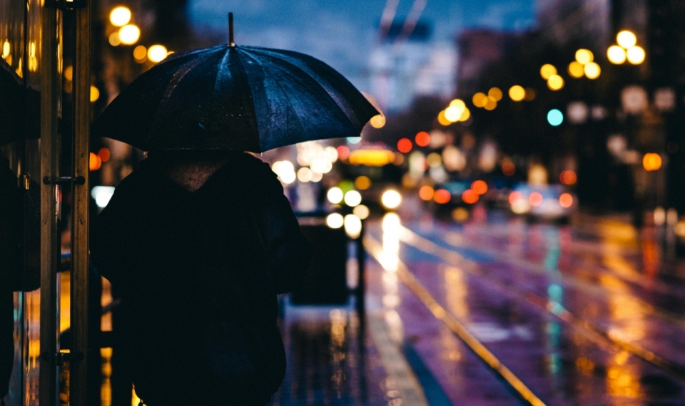 撑着雨伞在城市中行走的人背影摄影
