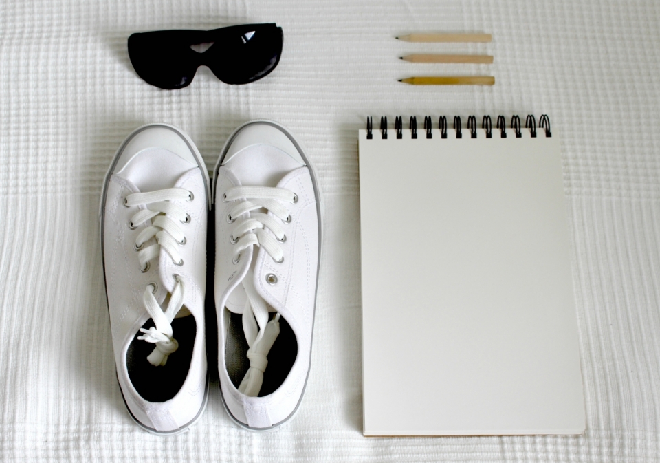 帆布鞋和笔记本在白色桌布上静物特写