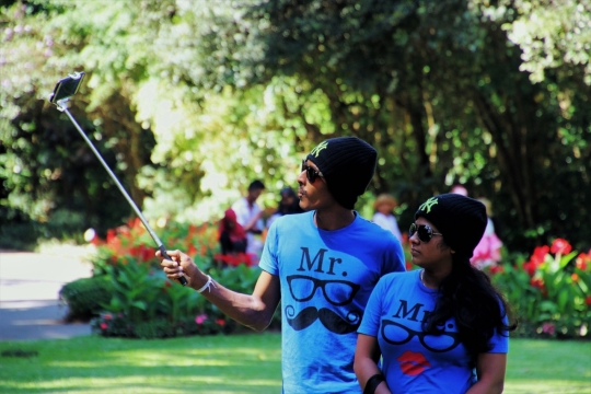 阳光户外举自拍杆合影穿情侣衫男女