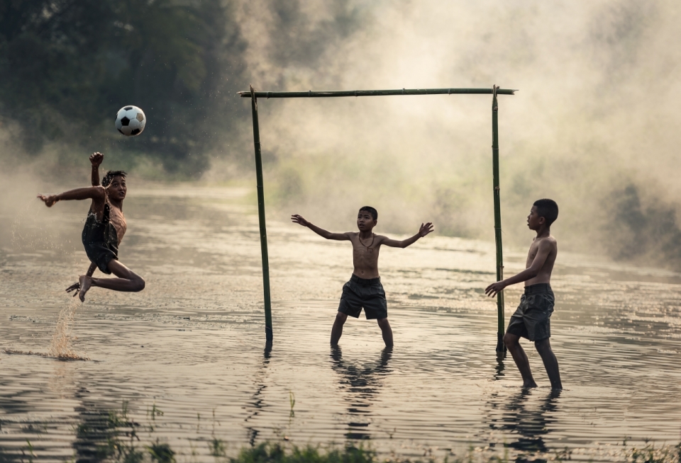 用木棍做球门3个孩子在水上踢足球