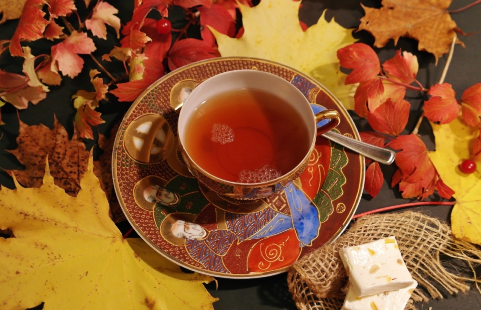 桌上散落着的红色枫叶与茶盏中的红茶