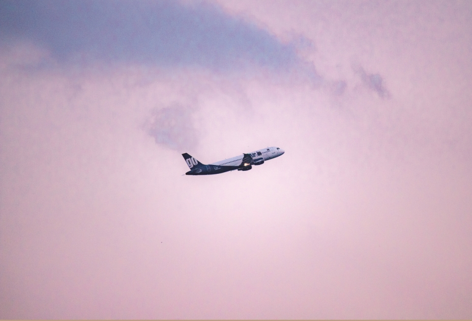 粉红色天空白云中起飞向上飞行的航空飞机