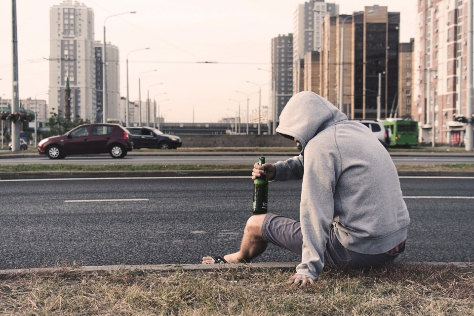 坐在公路边喝酒的男子背影