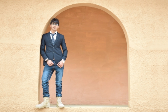 身着西装牛仔裤倚靠着站在拱门前的人