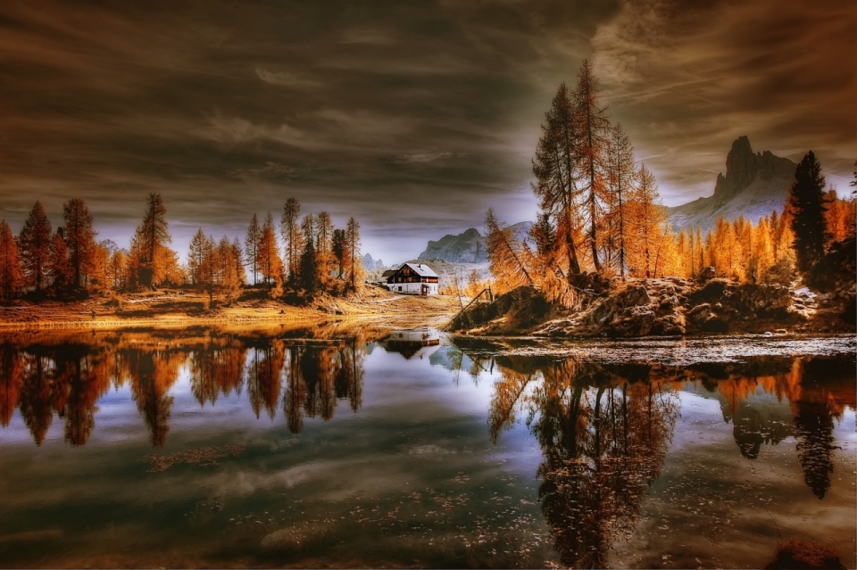 昏暗天空泛黄的树林房屋倒映在湖泊中