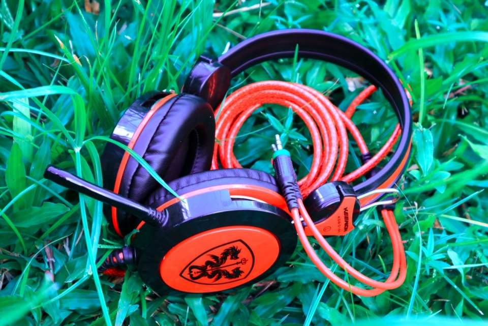绿色草地上摆放在黑色橘色相间的耳机静物摄影