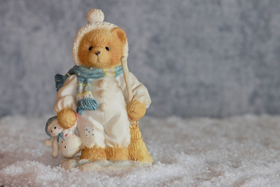 在雪地中拿着扫把的玩具泰迪熊