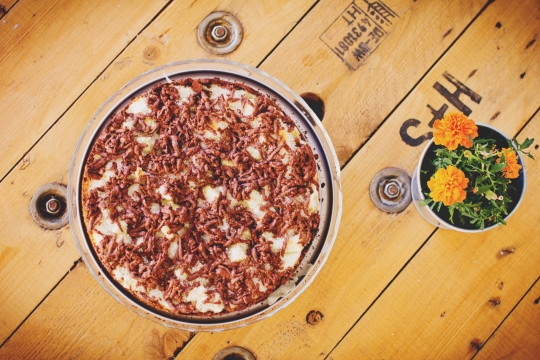 放在木桌上餐盘中的披萨与花盆中的小花