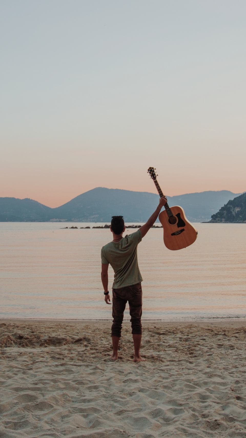 海边举着吉他眺望远方的男人背影