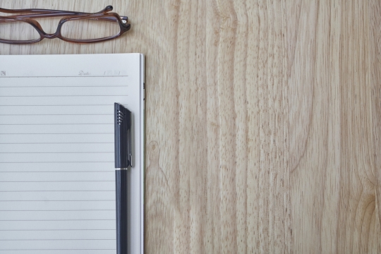 木制桌面笔记本黑色笔棕色边框眼镜