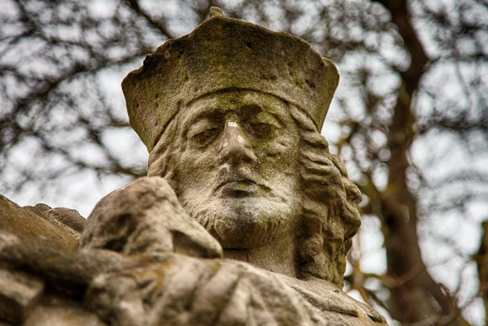 树林中戴帽子长卷发男性石质雕像