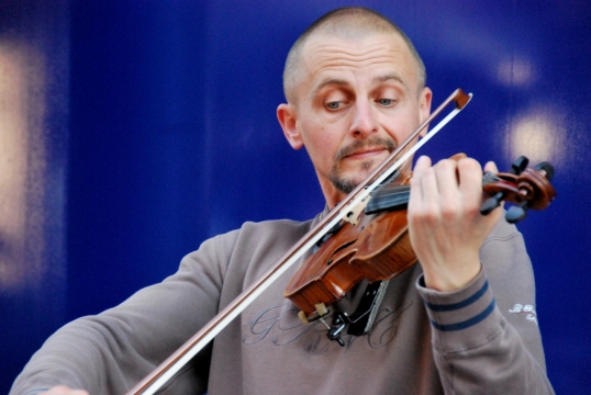 蓝色背景前正专注拉小提琴的人