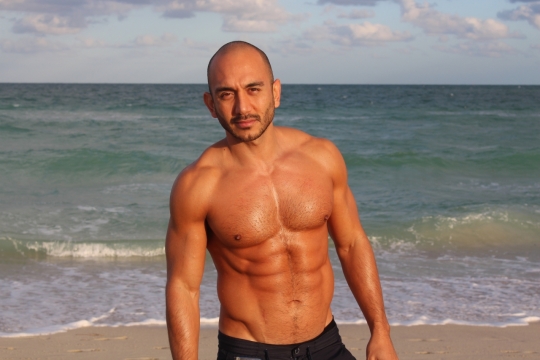 阳光下海边沙滩上的肌肉男子