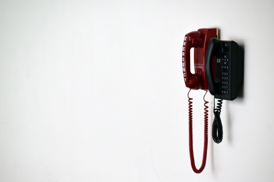 白色室内墙壁上红色黑色电话