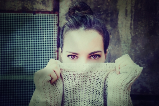 破旧墙壁前拉起毛衣遮脸的美女写真