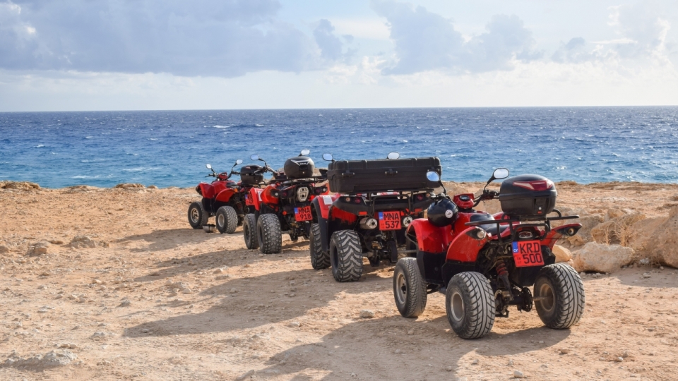 阳光下海边沙滩上停着四辆红色沙滩车