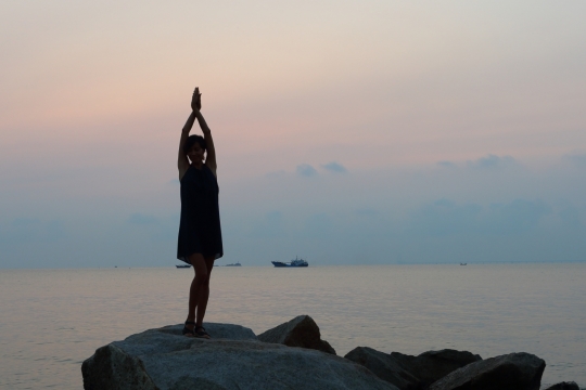 辽阔海边礁石站立瑜伽女性背影